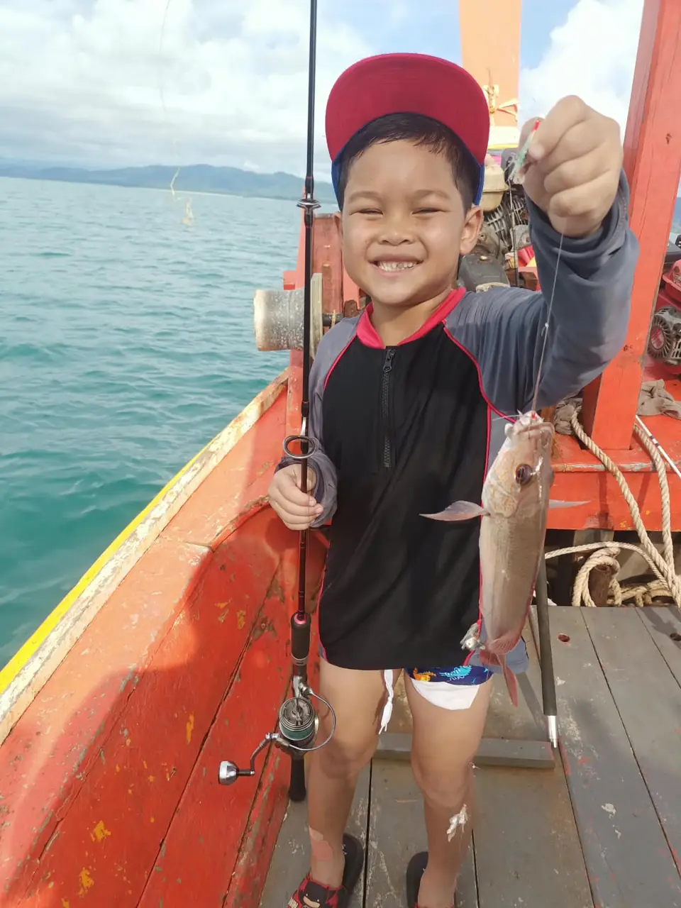 Guest showing a freshly caught fish aboard the fishing boat