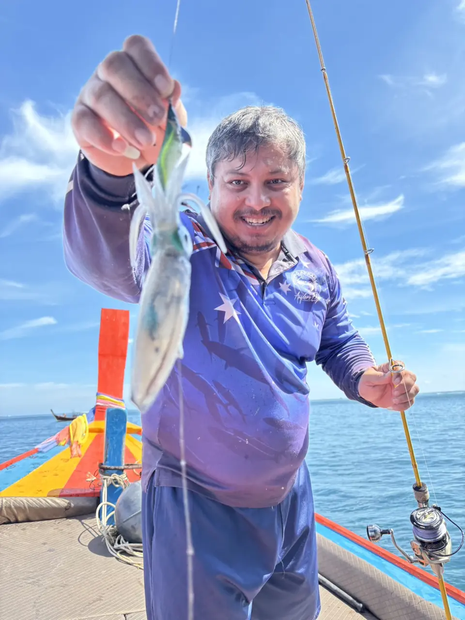 Guest showing a freshly caught fish aboard the fishing boat