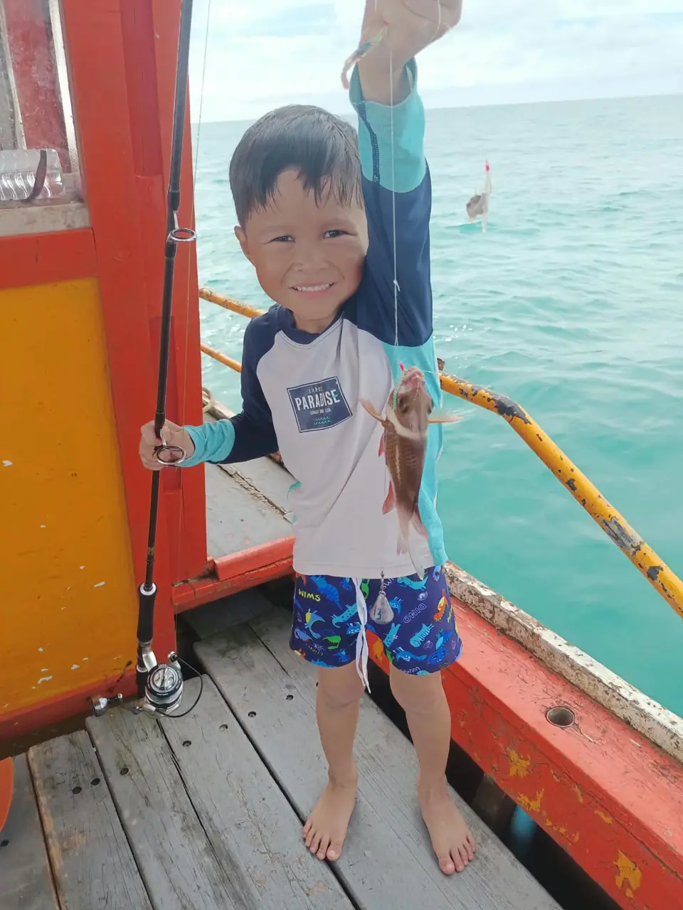 Guest showing a freshly caught fish aboard the fishing boat
