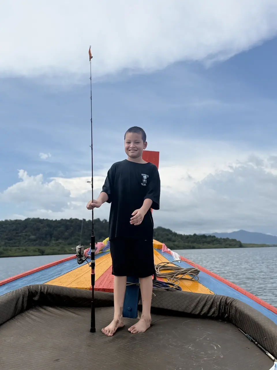 Guest showing a freshly caught fish aboard the fishing boat