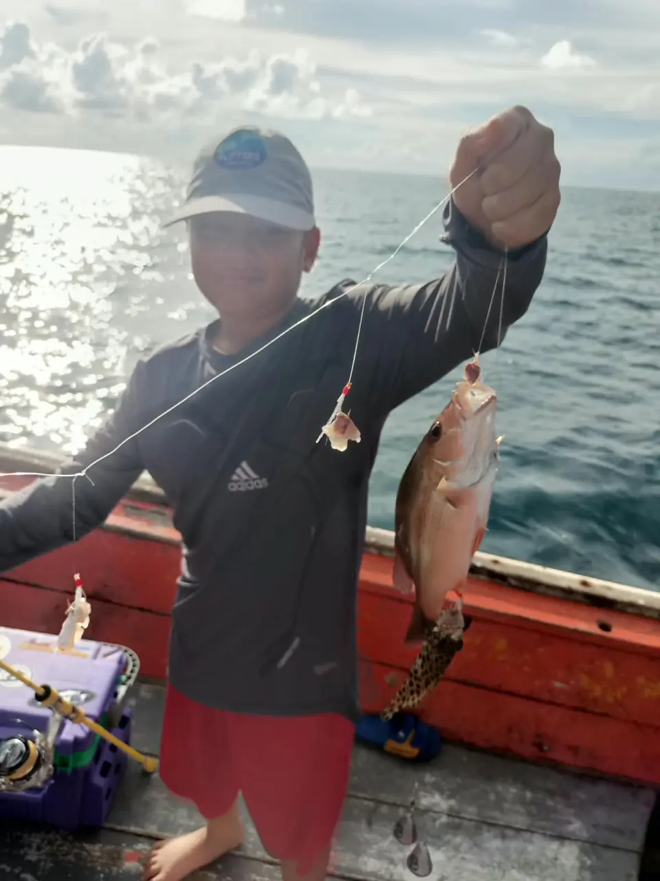Guest showing a freshly caught fish aboard the fishing boat