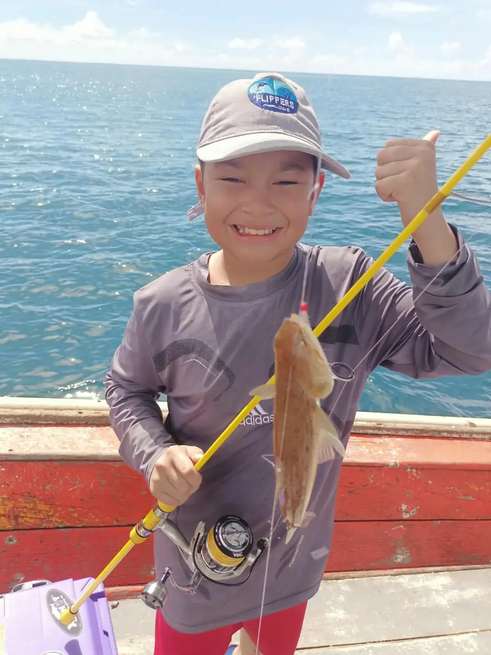 Guest showing a freshly caught fish aboard the fishing boat