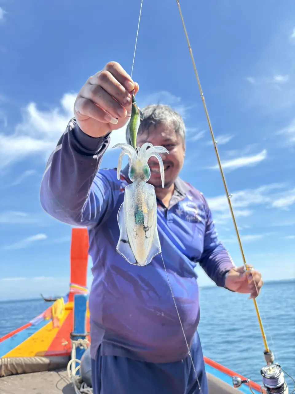 Guest showing a freshly caught fish aboard the fishing boat